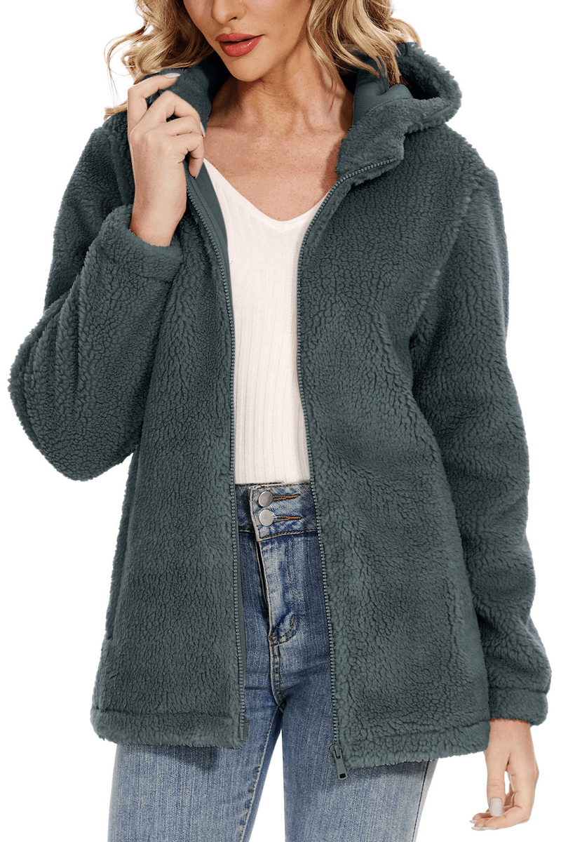 Woman wearing a stylish fluffy jacket with hood and zipper, SF0905, perfect for cold weather. Features pockets and high-quality polyester material.